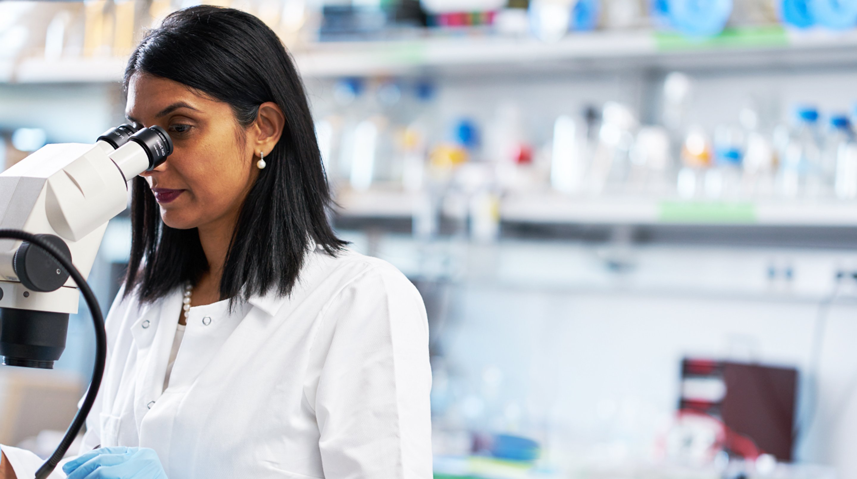 Researcher in a lab looking into a microscope as part of the U C S F error message page.